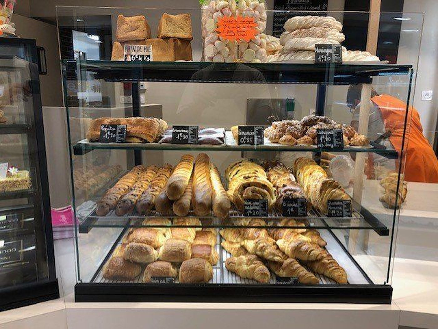 Vitrine de boulangerie garnie de croissants, de baguettes, de pains et de brioches.